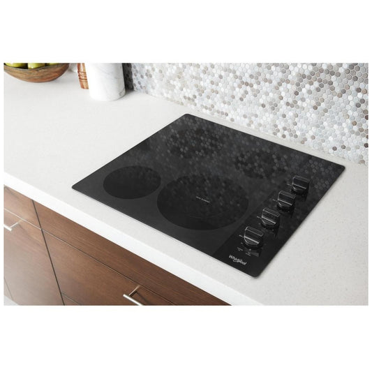 Top-down view of a 24-inch electric cooktop featuring four burners and a smooth black glass surface.